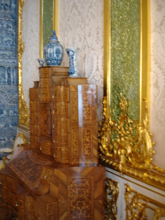a room with gold and blue wallpaper, golden furniture, a mirror and two large mirrors