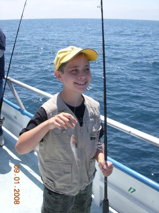 a small boy is holding onto some fish while standing on a boat