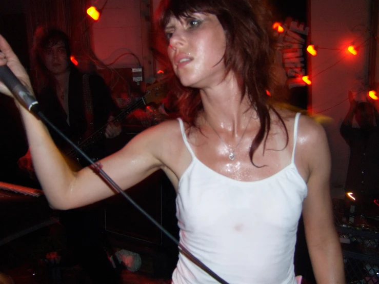 a woman wearing a white tank top holding a pair of scissors