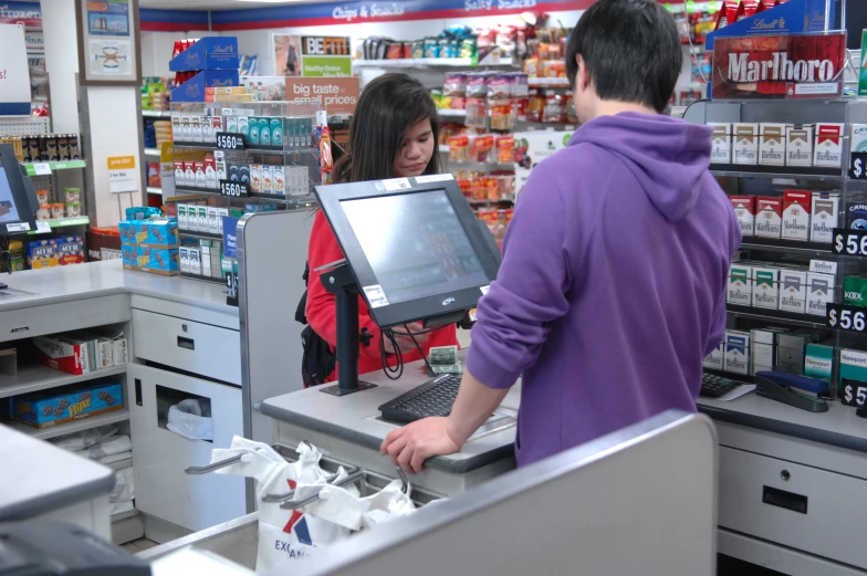 two customers are standing behind a laptop at the store