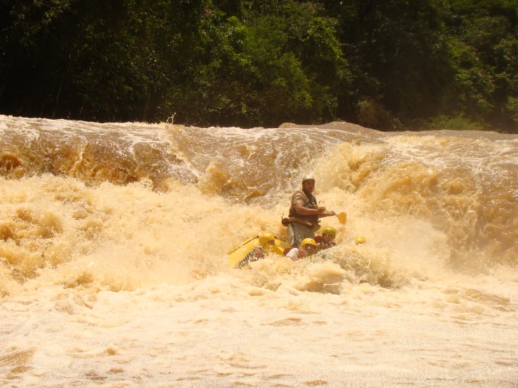 man in the water on a raft with a large yellow boat