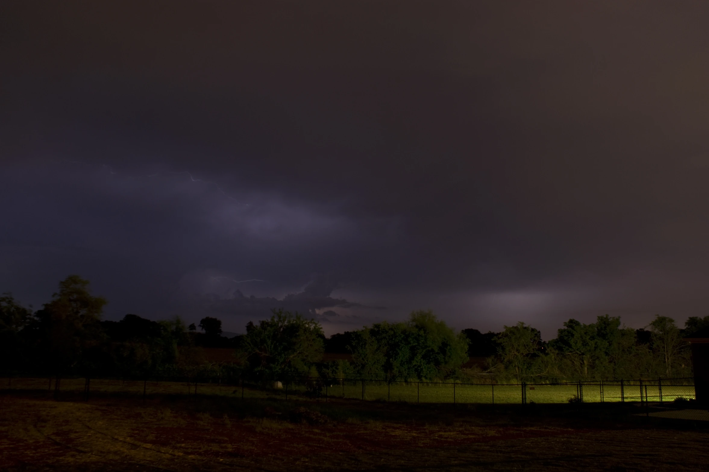 a dark stormy night is seen over an agricultural field