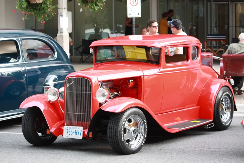 an antique red car sits next to a classic blue car