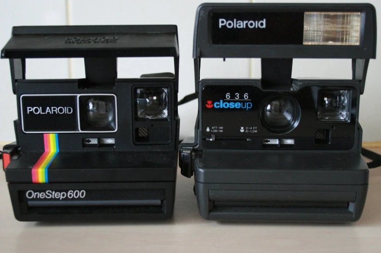 two polaroid cameras with rainbow stripes are sitting on top of each other