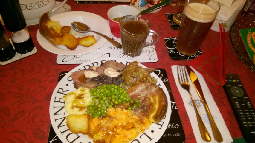 the plate contains meat and potatoes with green peas