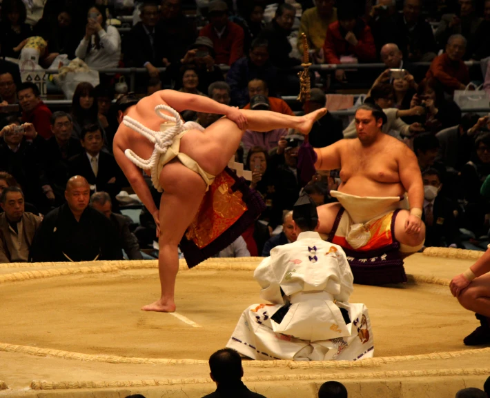 two sumo wrestlers are doing tricks in front of an audience