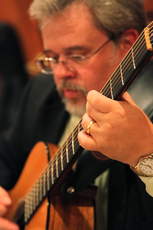 a man holding a black guitar and a watch