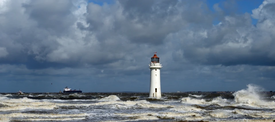 lighthouse surrounded by water with boats nearby under stormy clouds