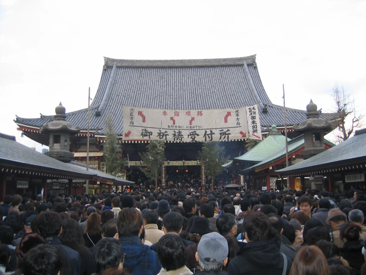 people are gathered in front of a large asian structure