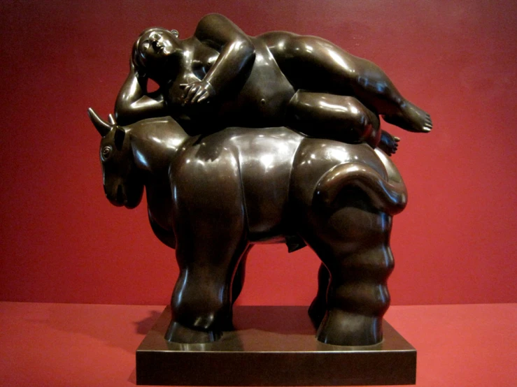 a sculpture of a woman laying on top of a bear