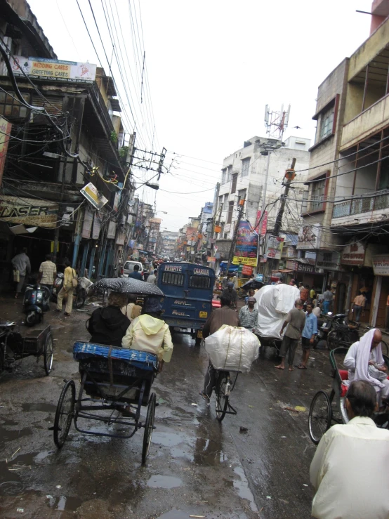 people walking around on a rainy street and riding carts