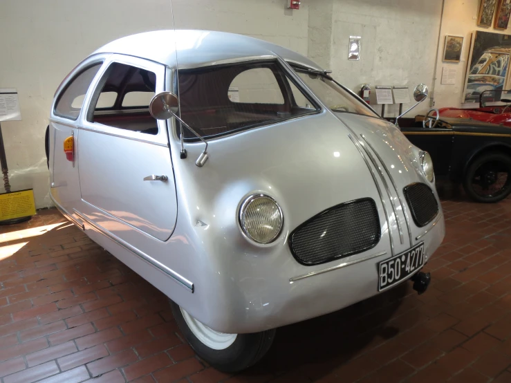 a classic car parked in a building with people looking at it