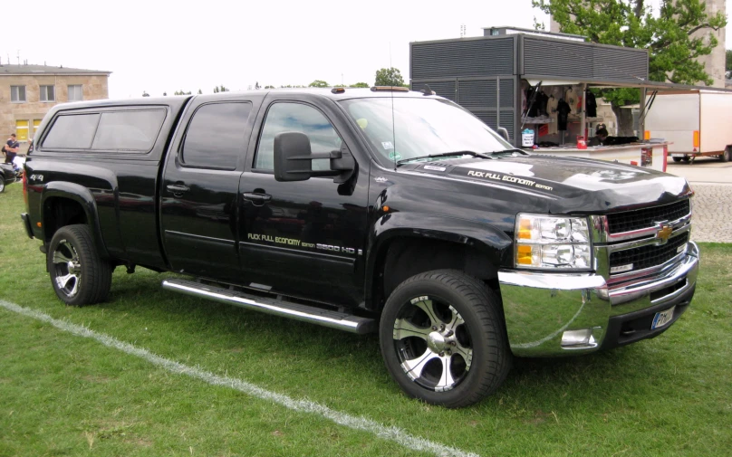 a black pickup truck parked on top of a lush green field