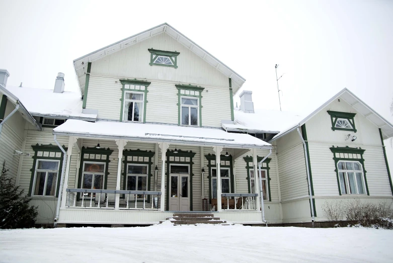 an older house is covered in snow and green trim
