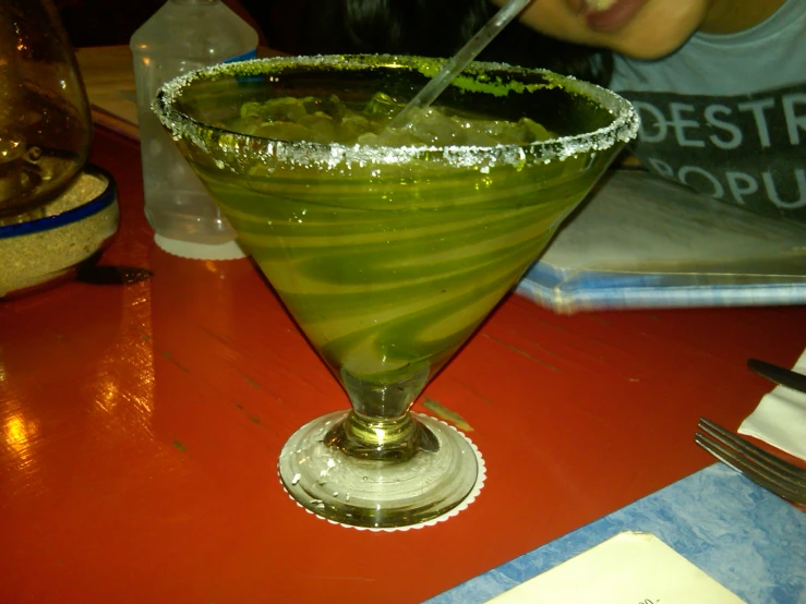 a woman sitting at a table in front of a green cocktail