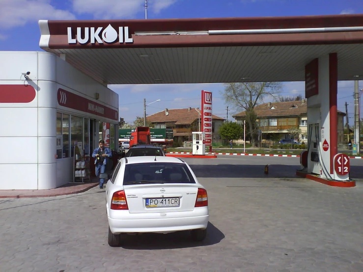 two cars parked in front of a fuel station