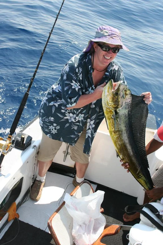 a woman holding a fish with two people watching