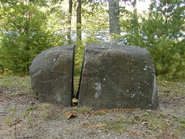 an open rock in the middle of a field with some trees