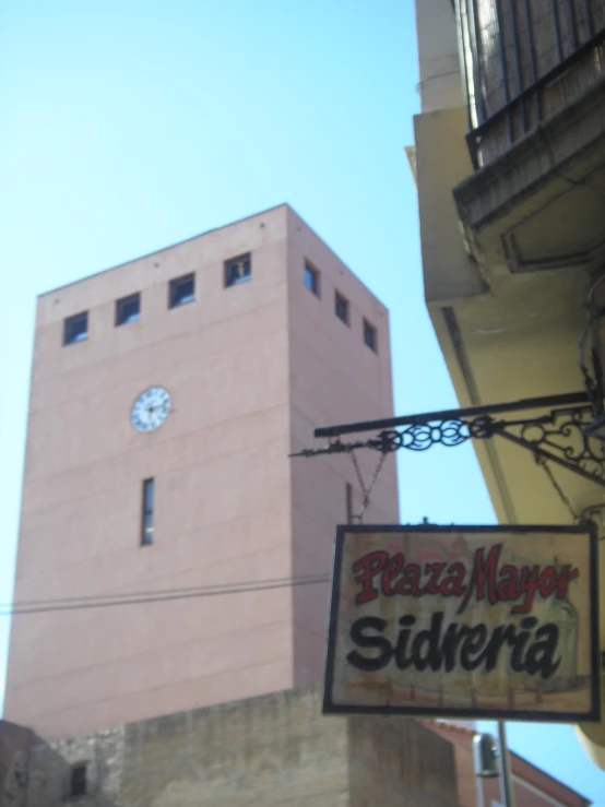 a clock tower sits above a pink building