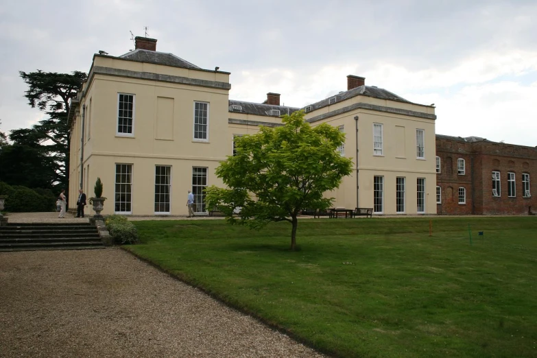 an old two story house with the grounds and trees in front