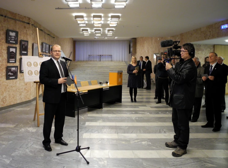 a man speaking in front of people while standing around