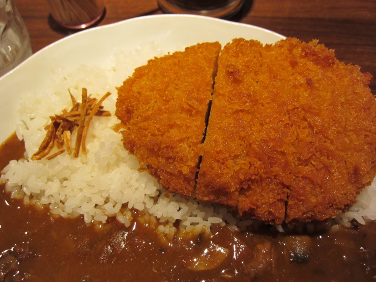 the rice is covered in gravy and fried meat