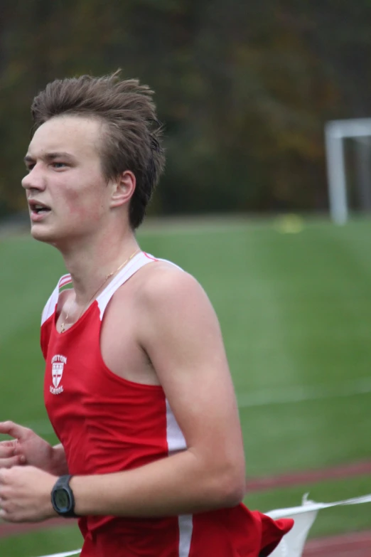 a young man running on a track with trees in the background