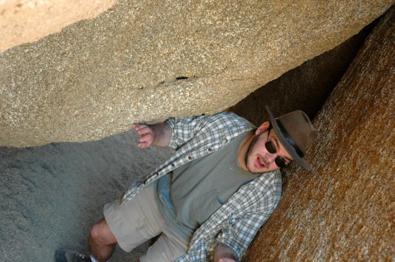 a man sitting next to large rocks and a huge rock