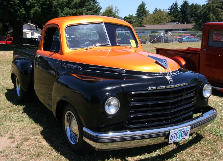 this is an old, black and orange truck parked in the grass