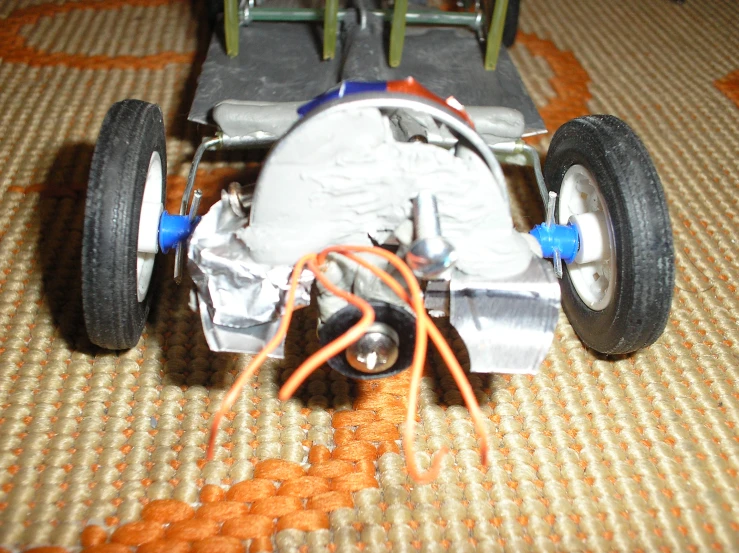 the plastic model has four wheels and many orange wires connected to it