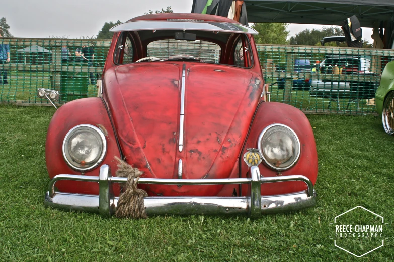 an old red car parked in the grass