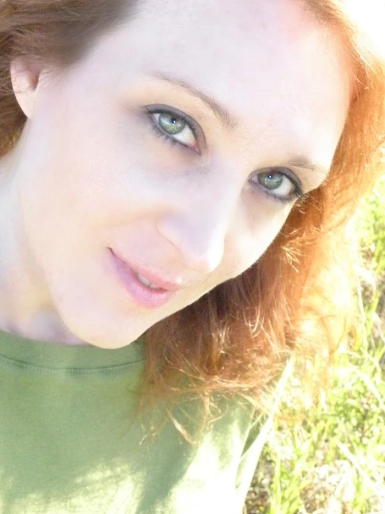 a woman with green eyes and a green shirt is posing for the camera