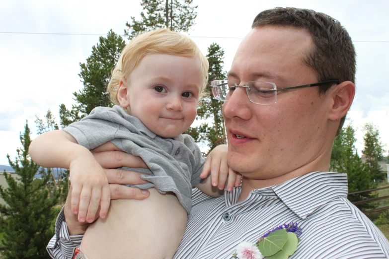 a man holds a toddler boy while posing for the camera