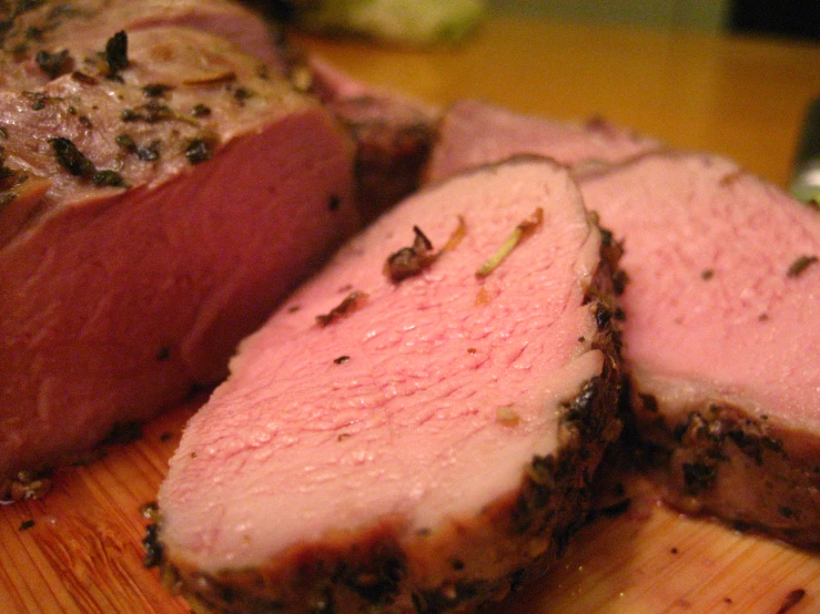 sliced meat is sitting on top of a wooden  board