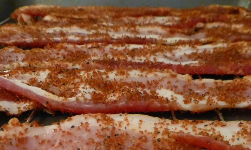 a pair of bacon strips are covered in parmesan