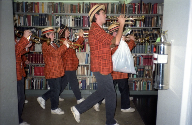 a group of men in red and black plaid shirts standing around a book shelf