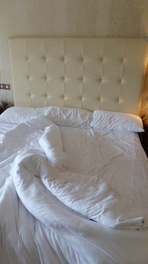 a bed with white sheets and a white headboard