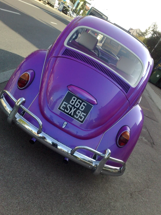 a very shiny old model purple car that is parked