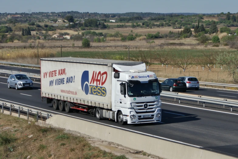 a semi truck driving down a road next to other cars