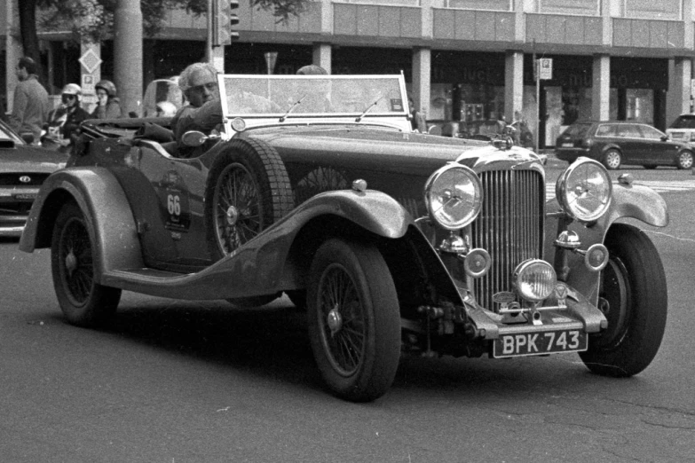 an old fashioned car is shown with several people in it