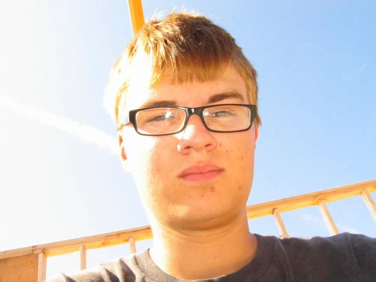 a young man wearing glasses while standing next to a ladder