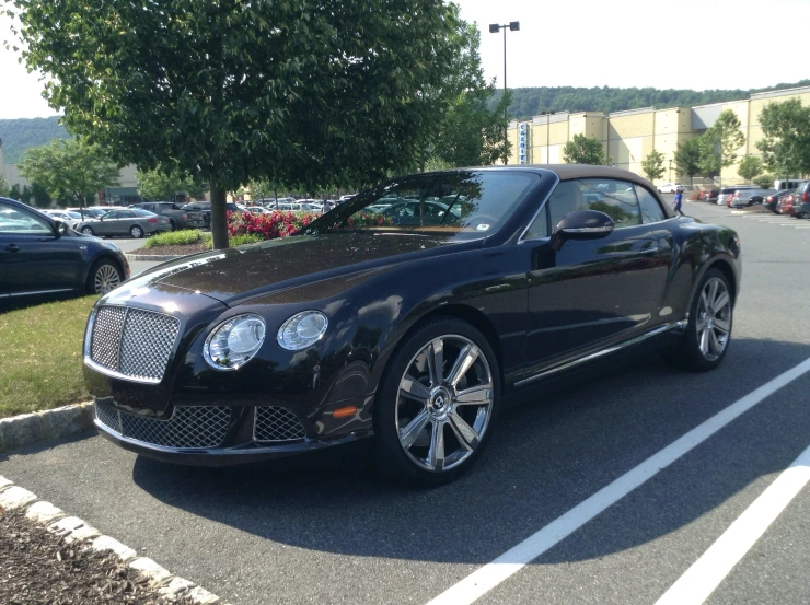 a black bentley sitting in a parking lot