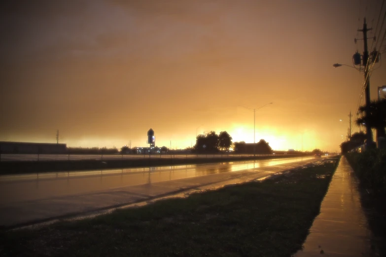 the sun is setting over a wet road