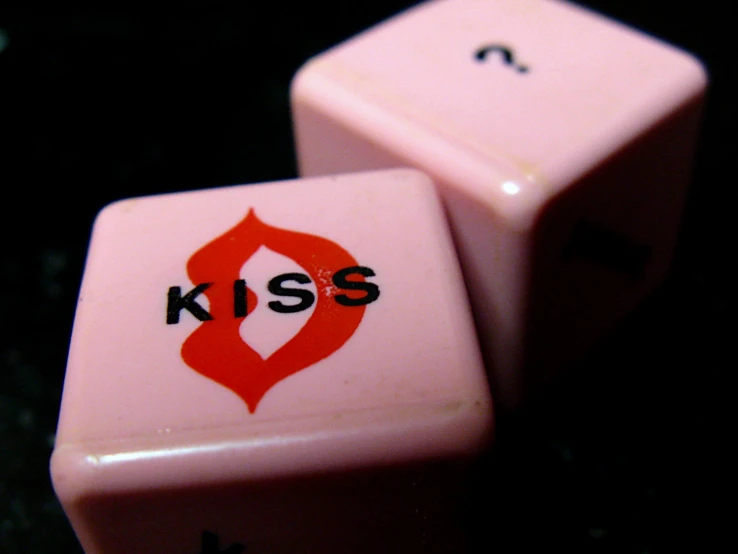 two pink dices that say kiss and are in the shape of heart