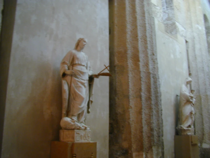 a statue of a monk with a cross on his left arm and arms wrapped around him holding a cane