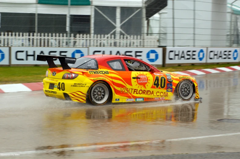 a red race car drives down a wet street