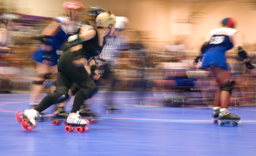 several people on roller skates riding on a blue surface