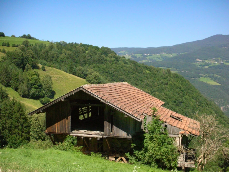 an old barn sits on the side of the hill