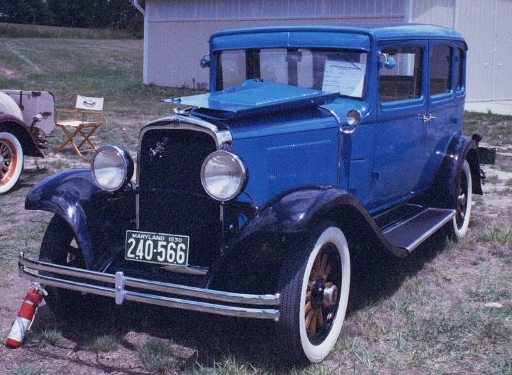 an old fashioned blue truck is parked on the grass