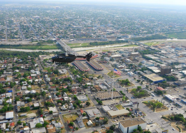 a black plane flying in the air over a city